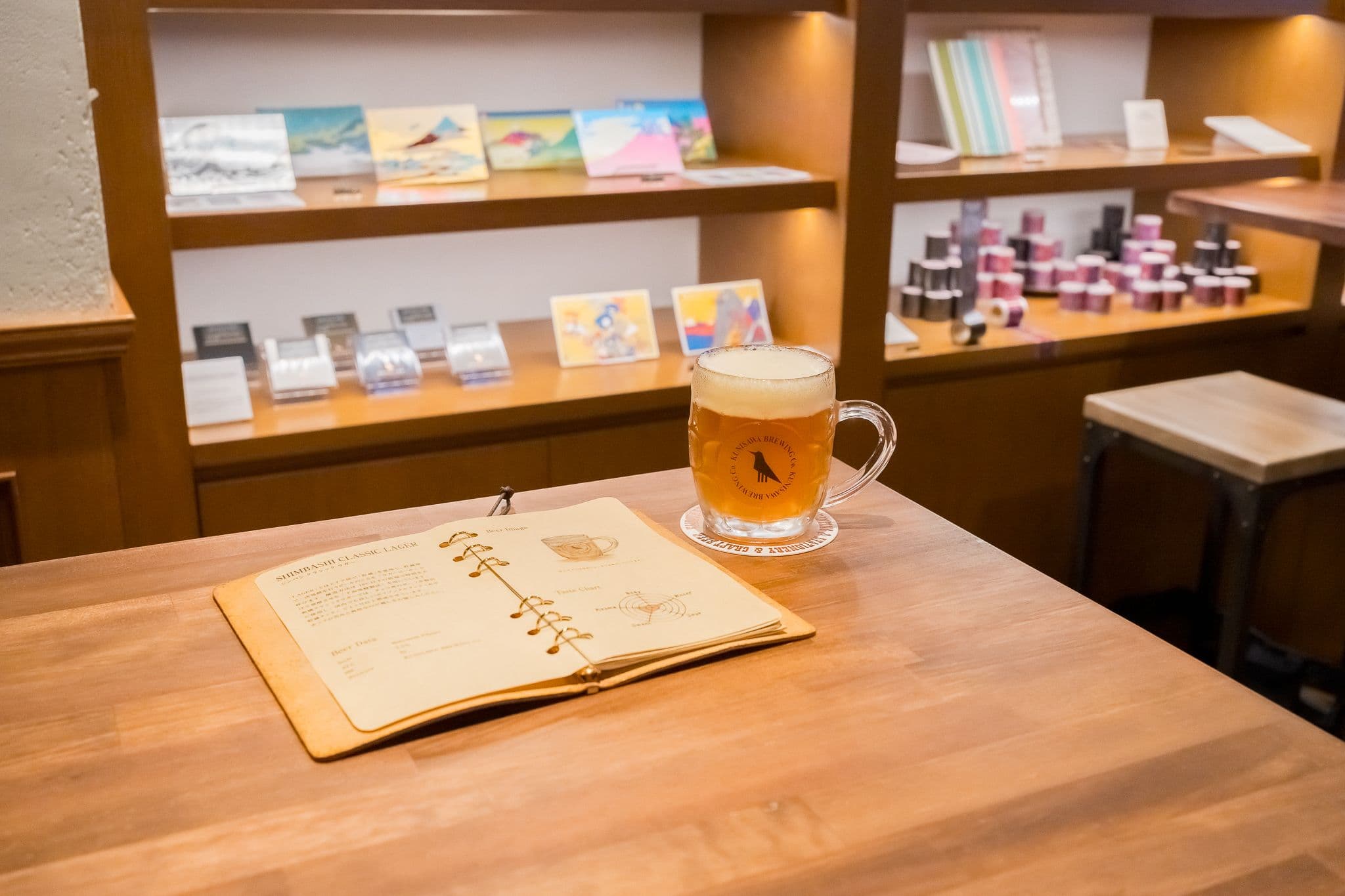 A fresh draught beer sits on a table next to a notebook